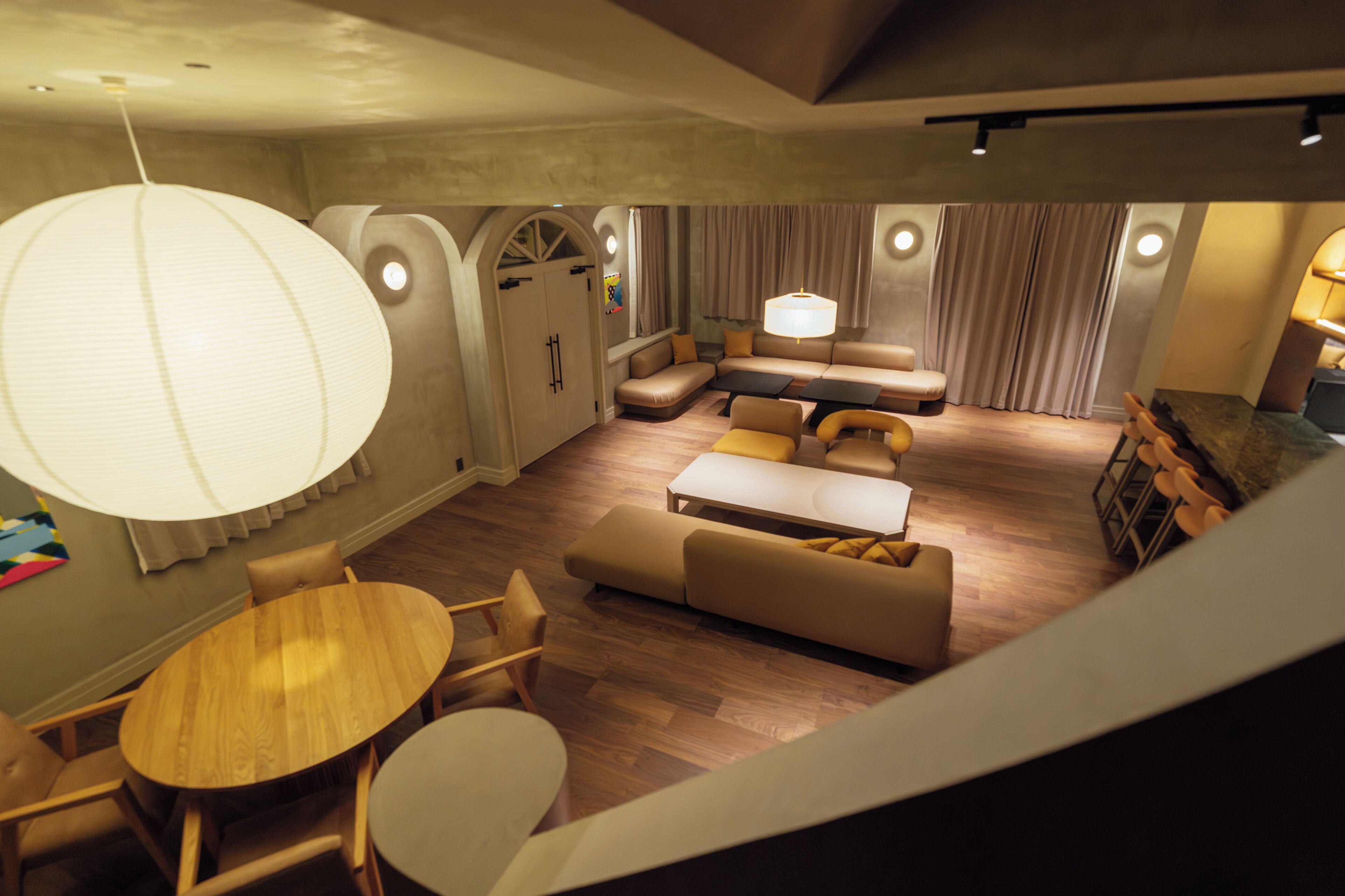 Ein modernes Wohnzimmer mit einem runden Esstisch, Sofas und einer großen Pendelleuchte.