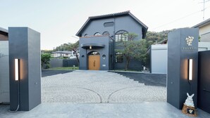 Um edifício com fachada escura, porta de madeira e uma placa com caracteres japoneses.