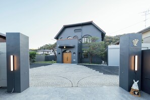 Ein Gebäude mit dunkler Fassade, einer Holztür und einem Schild mit japanischen Schriftzeichen.