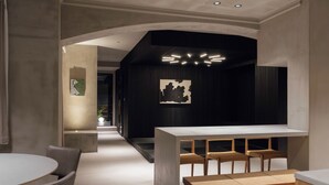 Um interior moderno com um bar central, assentos e um corredor que leva a outro espaço.