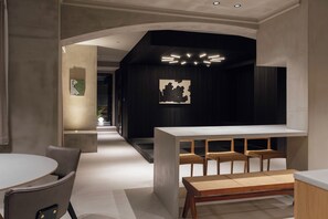 Ein modernes Interieur mit einer zentralen Bar, Sitzgelegenheiten und einem Gang zu einem weiteren Raum.