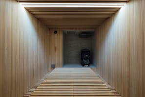 Una habitación estrecha con paneles de madera, una banca al fondo y una chimenea en el centro.