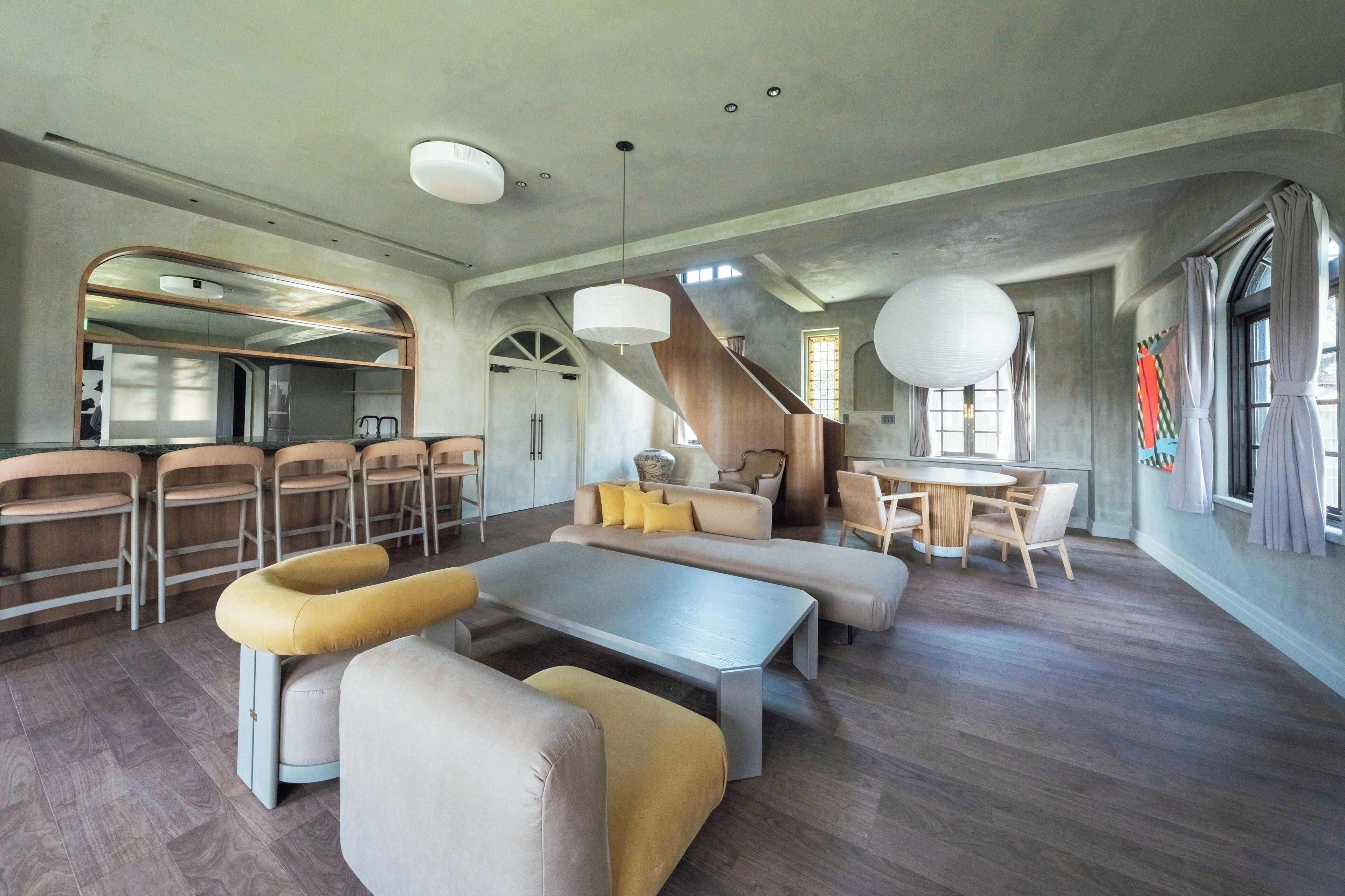 Un vaste espace de vie doté d’un haut plafond, d’un escalier et d’un coin repas avec des chaises et une table.