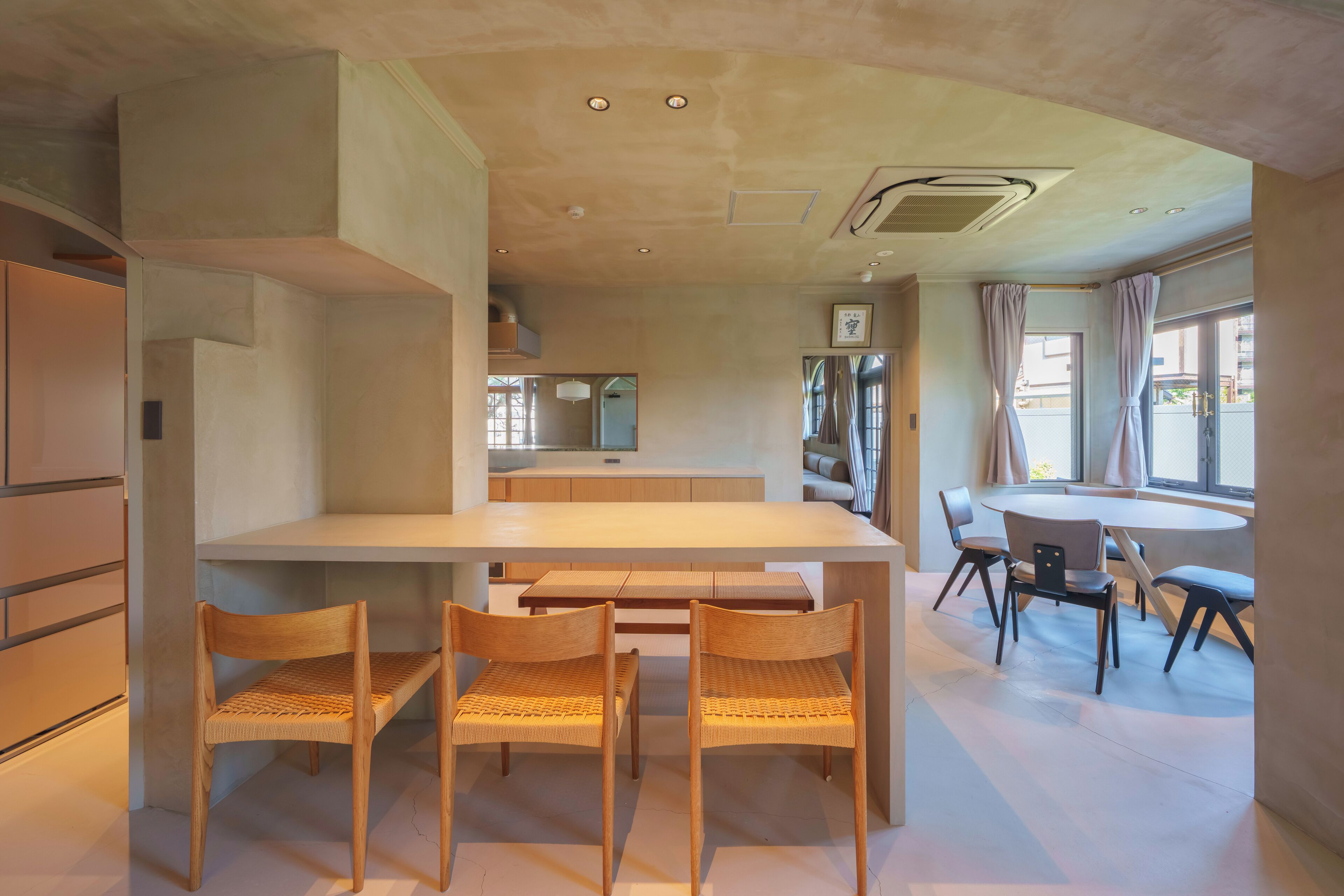 A modern kitchen with a central island, wooden chairs, and a dining area with a round table and chairs.