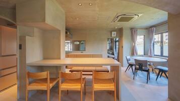 A modern kitchen with a central island, wooden chairs, and a dining area with a round table and chairs.