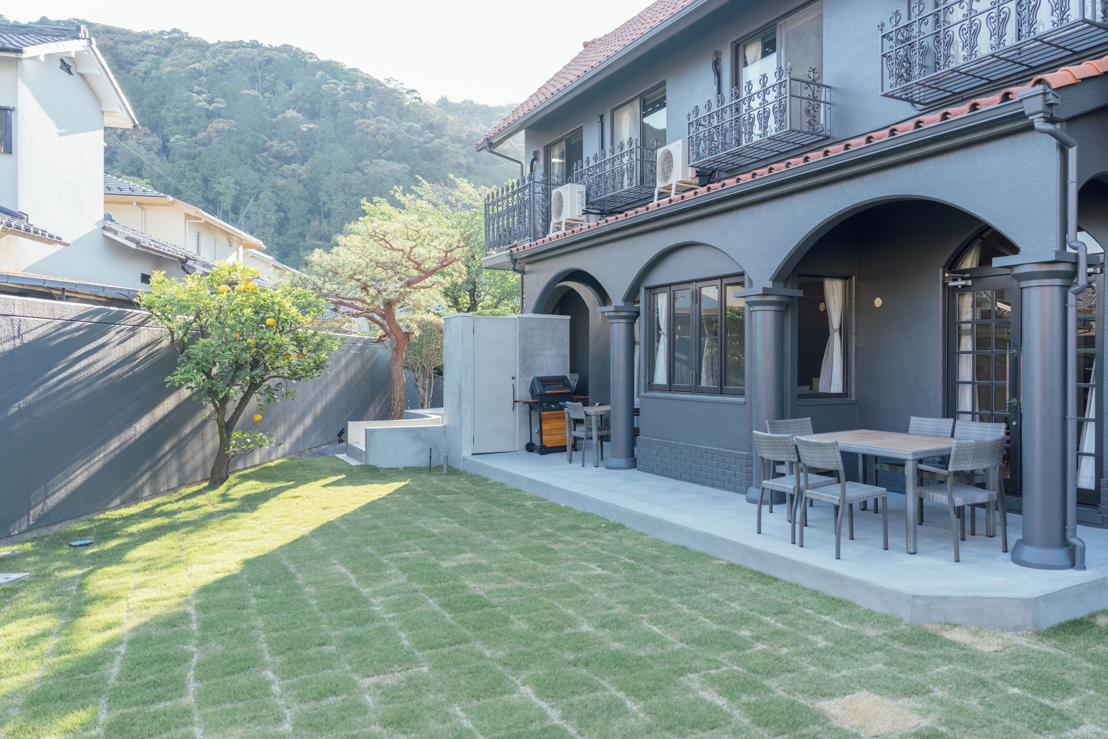 Una propiedad residencial con patio, mobiliario exterior y una parrilla.