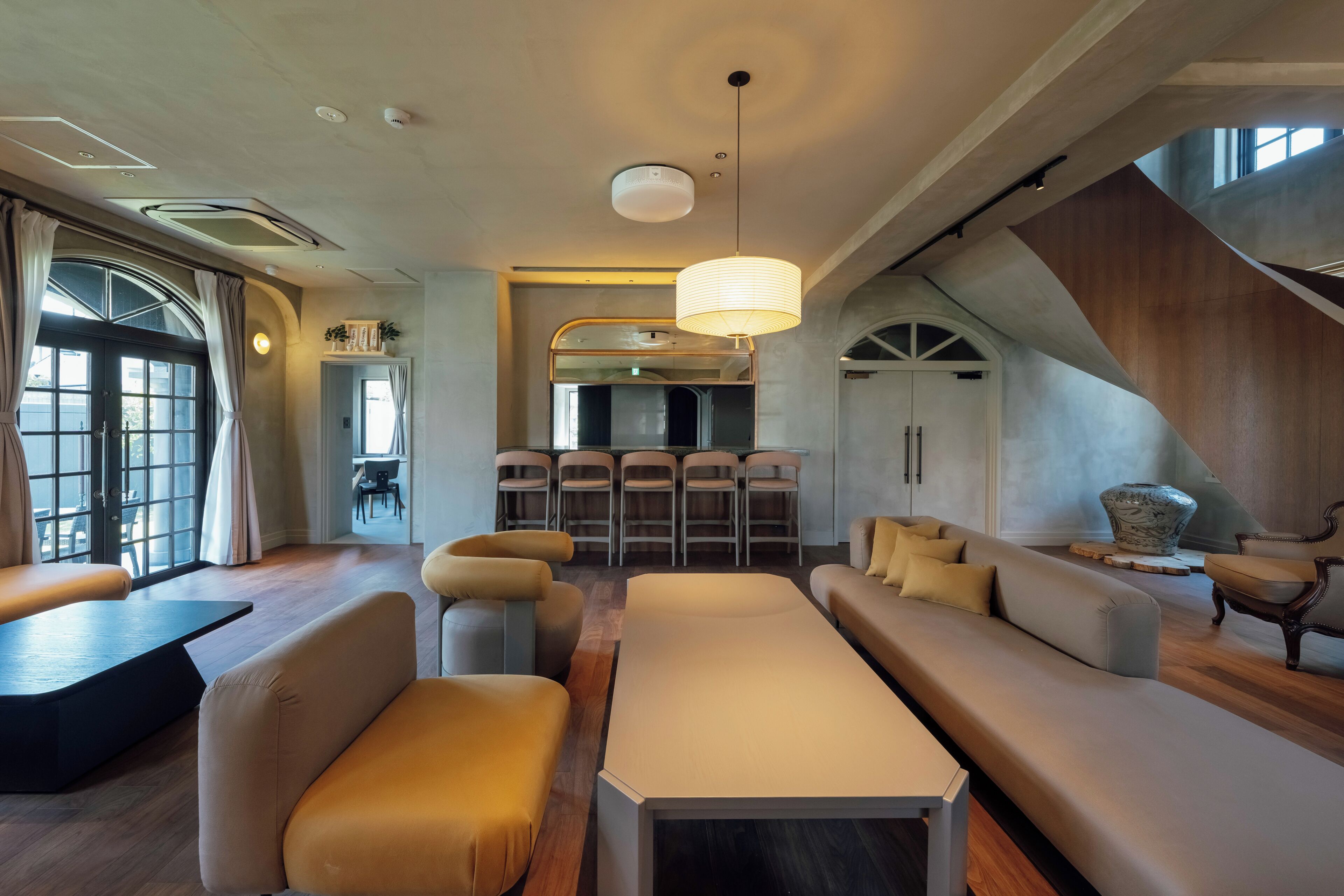 A modern interior with a seating area, a kitchen, and a staircase.