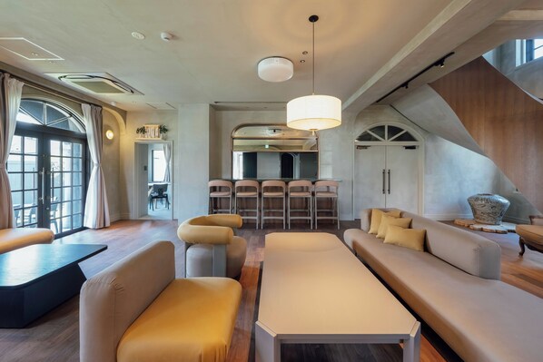 A modern interior with seating areas, a dining space, and a staircase.