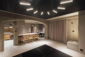 Un interior moderno con cocina, comedor y un amplio sofá modular negro.