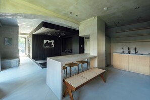 A modern kitchen with a central island, bar stools, and a built-in refrigerator.