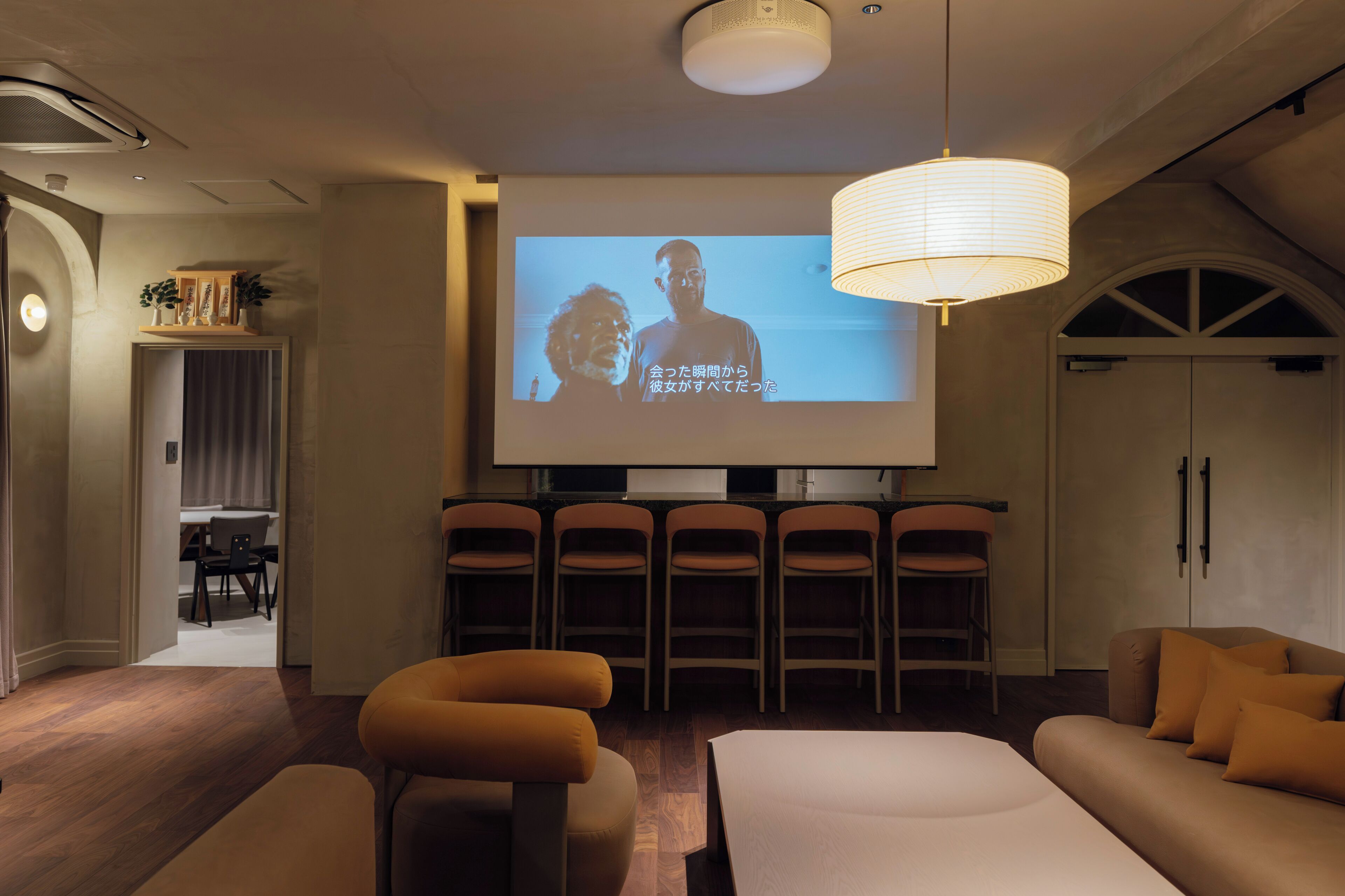 A modern lounge area with a flat-screen TV, comfortable seating, and a ceiling-mounted light fixture.