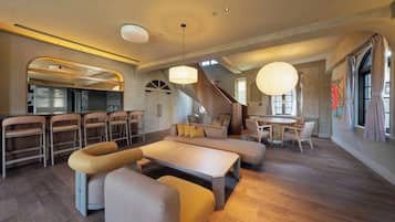 A spacious living area with a dining table, sofas, and a staircase.