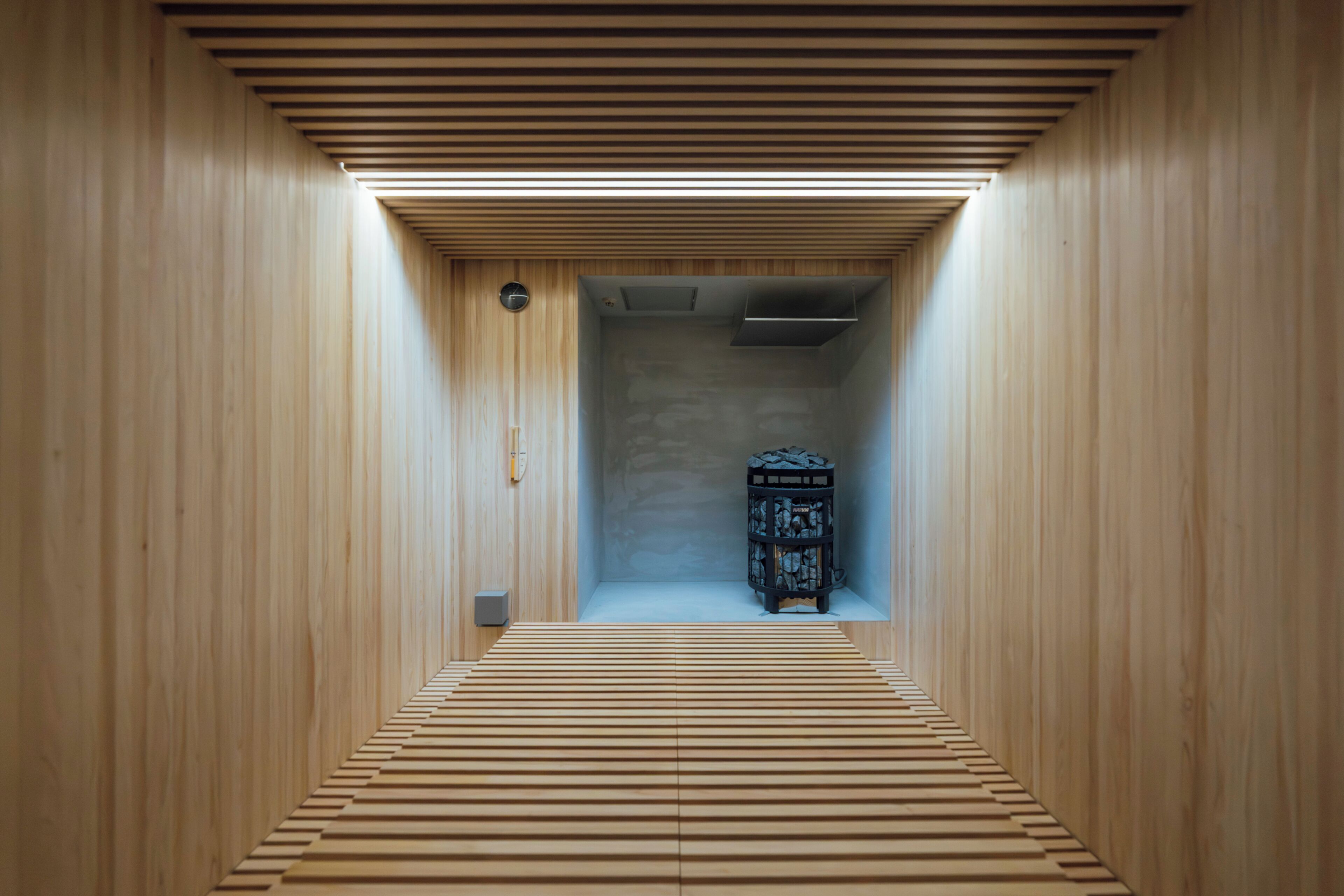 Un couloir étroit aux murs en bois et au plancher à lattes mène à une pièce dotée d’une cheminée.