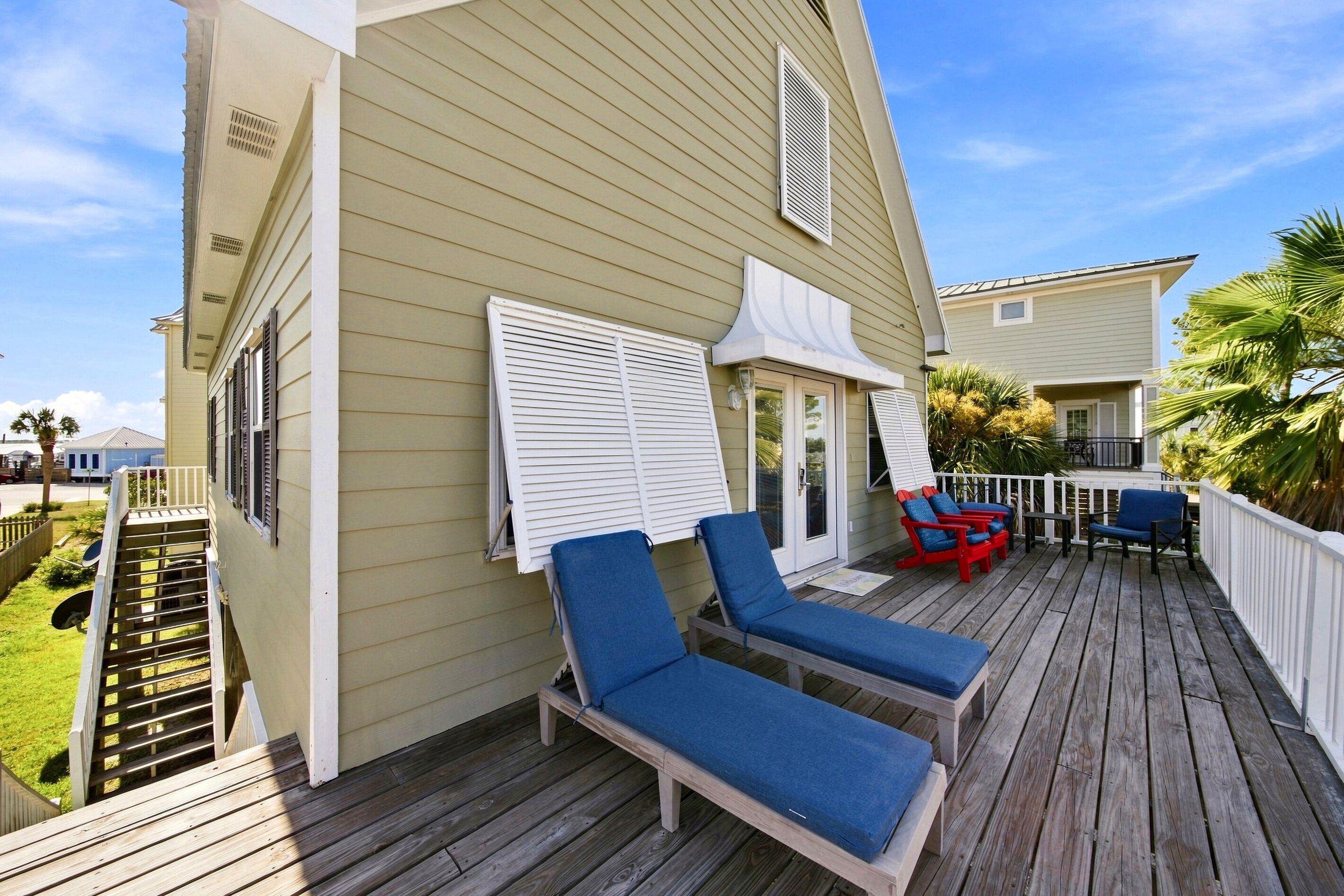 A deck with two lounge chairs, a small table, and a red chair.