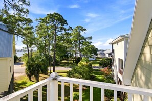 A residential area with multiple houses, a clear sky, and a view of a body of water in the distance. - 5783 Pensacola Ave | Bear Point | Sleeps 9 (Orange Beach)