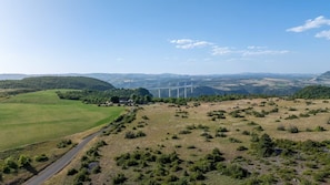 Ländliche Landschaft mit einer Straße, Feldern und Windkraftanlagen in der Ferne.