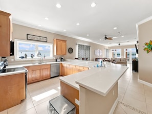A spacious kitchen with wooden cabinets, a large island, and a view to the outside. - Eagles Nest | Sleeps 10 | Bay Views Pet-Friendly (Gulf Shores)
