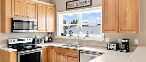 A kitchen with wooden cabinets, stainless steel appliances, a window with a view, and a sign above the window.