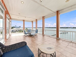 A covered outdoor area with a view of the water, furnished with a table and chairs. - Eagles Nest | Sleeps 10 | Bay Views Pet-Friendly (Gulf Shores)