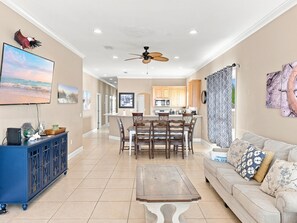 A spacious living area with a dining table, a sofa, and a television mounted on the wall. - Eagles Nest | Sleeps 10 | Bay Views Pet-Friendly (Gulf Shores)