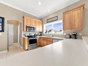 A modern kitchen with wooden cabinets, stainless steel appliances, and a large window. - Eagles Nest | Sleeps 10 | Bay Views Pet-Friendly (Gulf Shores)
