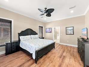 A bedroom with a bed, a nightstand, a dresser, a ceiling fan, and a door leading to another room. - Eagles Nest | Sleeps 10 | Bay Views Pet-Friendly (Gulf Shores)