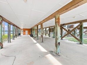 An indoor space with a concrete floor, wooden beams, and a view of the outdoors. - Eagles Nest | Sleeps 10 | Bay Views Pet-Friendly (Gulf Shores)