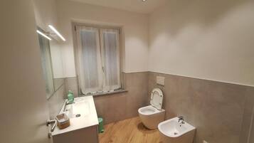 Ein Badezimmer mit Waschbecken, zwei Toiletten und einem Bidet.