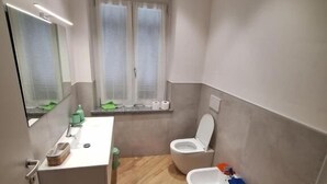 Ein kleines Badezimmer mit Toilette, Bidet und einer kompakten Waschtisch-Ecke.