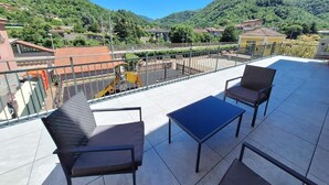 Eine Terrasse mit Gartenmöbeln und Blick auf eine gebirgige Landschaft.