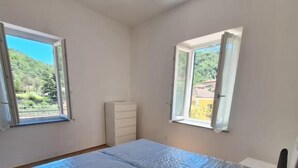 Ein Schlafzimmer mit einem Bett, zwei Fenstern, einem Schminktisch und einem Dachfenster.