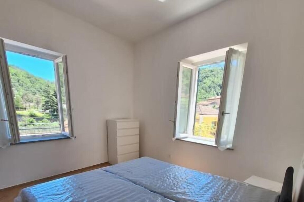 A bedroom with a bed, two windows, a dresser, and a skylight.
