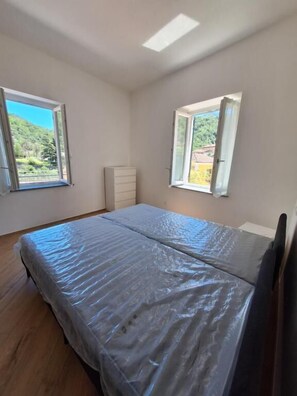 A bedroom with a bed, two windows, a dresser, and a skylight. - da sandra (Isola del Cantone)