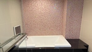 A modern bathroom with a large bathtub, a glass shower enclosure, and a tiled wall.