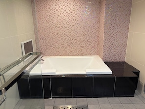 A modern bathroom with a large bathtub, a glass shower enclosure, and a tiled wall.