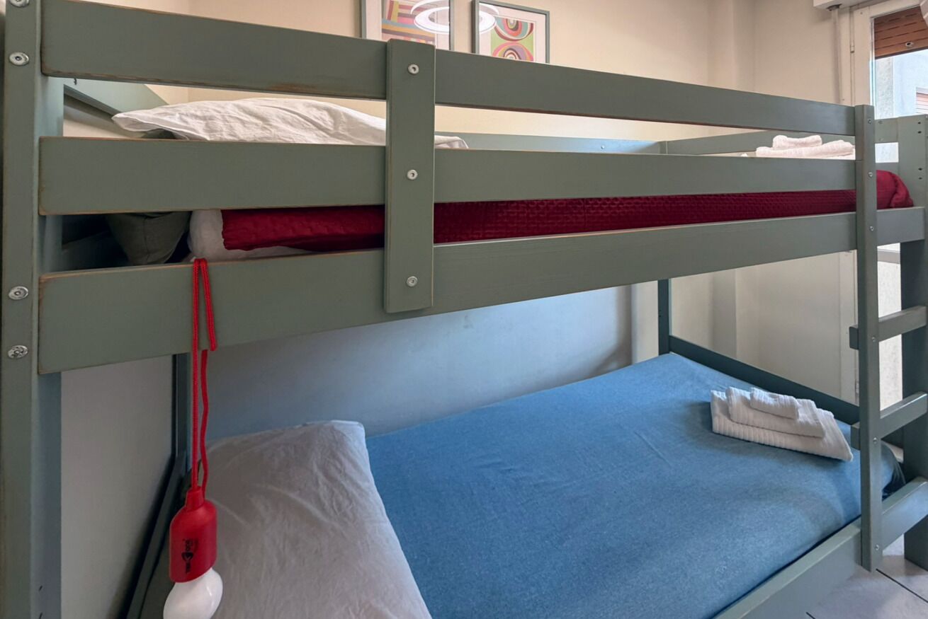 Una cama litera con colchón azul y cabecera roja.