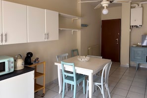 A small kitchen with a microwave, kettle, and kettle on a shelf. There is a dining table with chairs and a bowl on it. - A cozy and comfortable 49 square meters apartment, perfect for five people, located on the first floor of a building with an elevator (NOT accessible to people with disabilities).The property is situated within the Anna Maria residential complex in Lid (Lido Adriano)