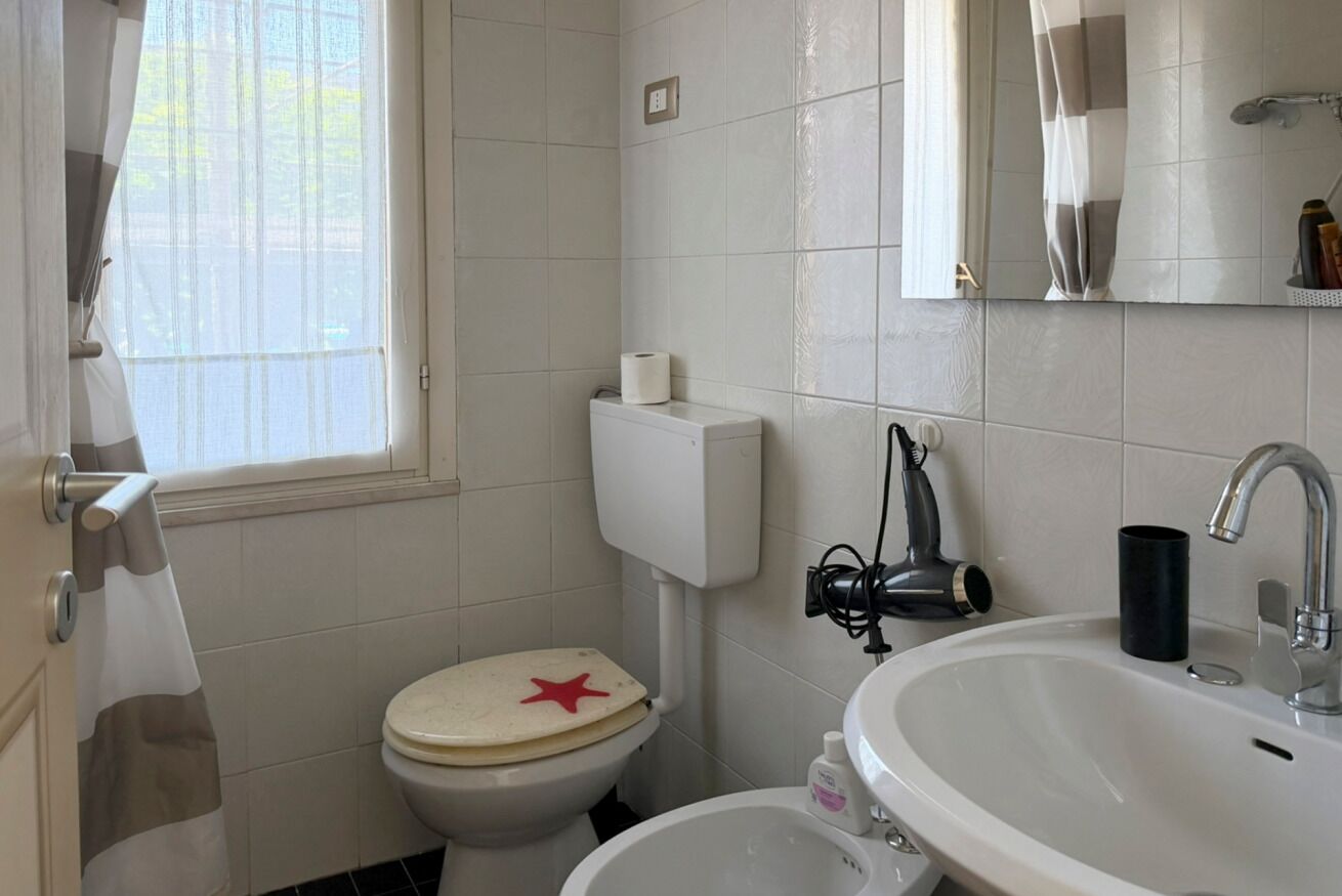 Un baño con inodoro, lavabo y ventana.