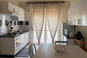 A modern kitchen with a gas stove, oven, and a dining area with a table and chairs. - A cozy and comfortable 49 square meters apartment, perfect for five people, located on the first floor of a building with an elevator (NOT accessible to people with disabilities).The property is situated within the Anna Maria residential complex in Lid (Lido Adriano)