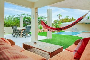 Une terrasse extérieure avec une piscine, un coin salon et un hamac.