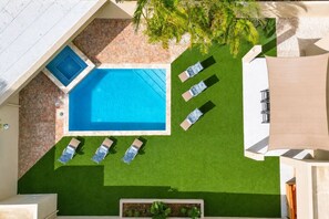 Ein Poolbereich auf dem Dach mit einem rechteckigen Pool, mehreren Liegestühlen und einem kleinen Garten mit Pflanzen.