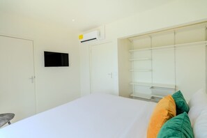 A bedroom with a bed, a wardrobe, a television, and an air conditioning unit. - Modern Two Villas • 6BR • 2 Private Pools • Aruba Escape (Noord)