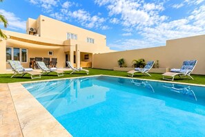 A swimming pool with lounge chairs and a building with a flat roof and large windows. - Modern Two Villas • 6BR • 2 Private Pools • Aruba Escape (Noord)