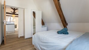 A bedroom with a sloped ceiling, a bed with white bedding, a blue towel, and a wooden ladder. - T2 élégant devant la mairie - calme - centre (Arras)