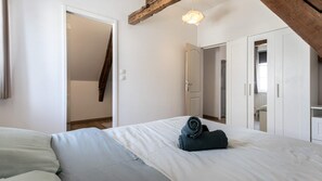 A bedroom with a bed, a wardrobe, and a door leading to another room. - T2 élégant devant la mairie - calme - centre (Arras)
