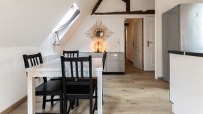 A modern kitchen with a white countertop, black chairs, and a wooden ceiling. - T2 élégant devant la mairie - calme - centre (Arras)
