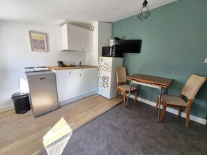 A compact kitchen with a dishwasher, refrigerator, microwave, and a dining area with a table and chairs. - Les toits de nationale, 2 personnes (Lille)