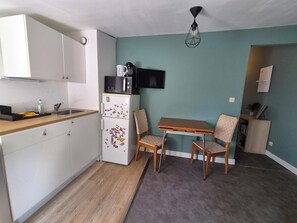 A compact kitchen with a refrigerator, microwave, and a small dining table with chairs. - Les toits de nationale, 2 personnes (Lille)