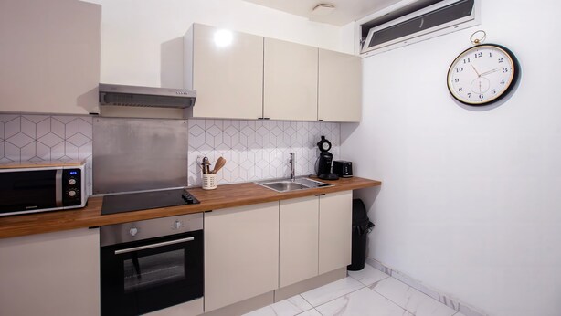 Una cucina moderna con microonde, forno, lavello e un orologio appeso al muro.