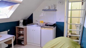 Kompakti keittiö, jossa on sisäänrakennettu astianpesukone, kahvinkeitin ja pieni hylly.